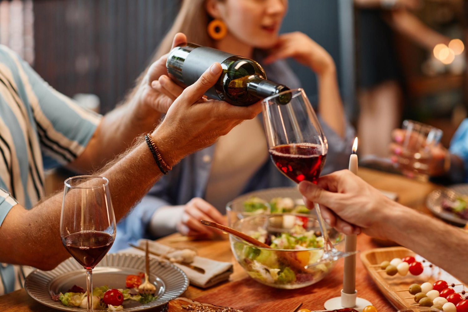 close-up-man-pouring-wine-into-glass-during-dinner-party-with-cozy-warm-setting(1)
